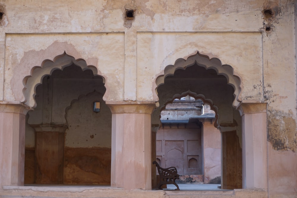 a stone building with arches and a bench