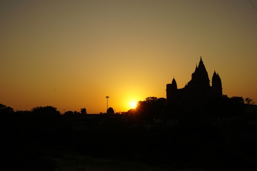 Sunset view of the Konark Sun Temple silhouetted against a vibrant orange sky.
