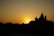 A stunning sunset over the ocean with silhouettes of temple structures in the foreground.