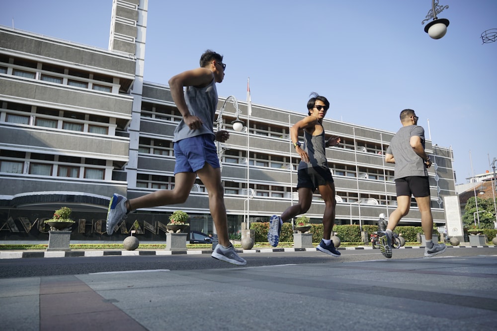 a group of people running down a street next to a tall building