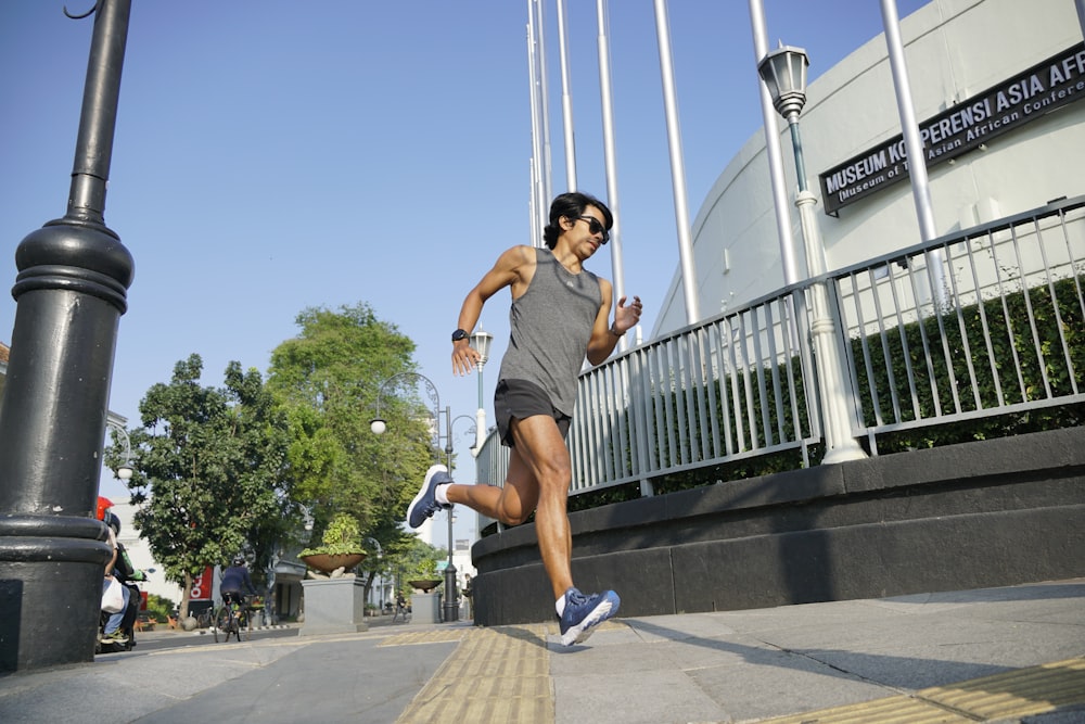 a man running down a sidewalk next to a street light