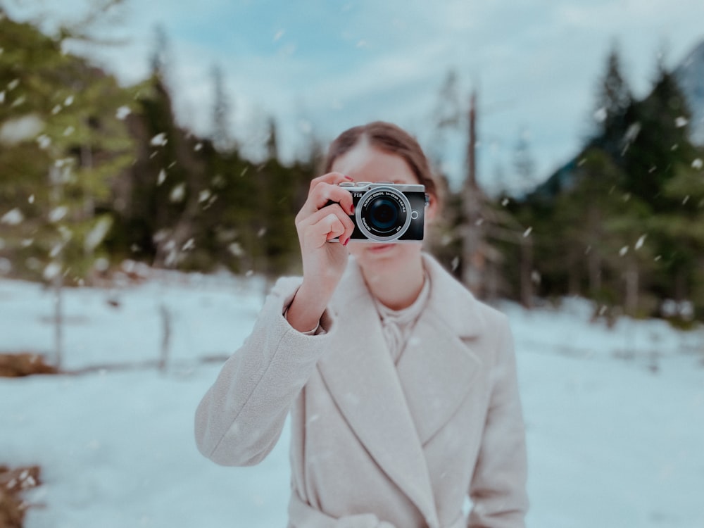 a woman taking a picture with a camera in the snow