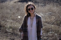 a woman standing in a field wearing sunglasses