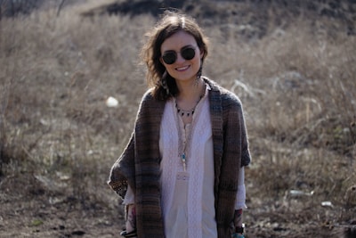 a woman standing in a field wearing sunglasses