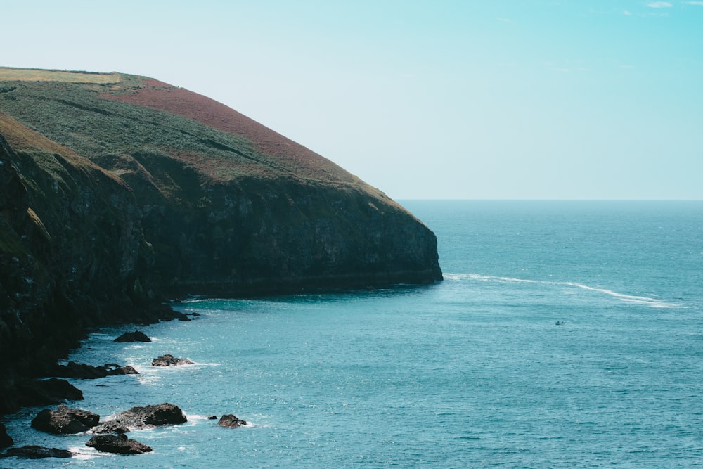 a body of water next to a rocky cliff