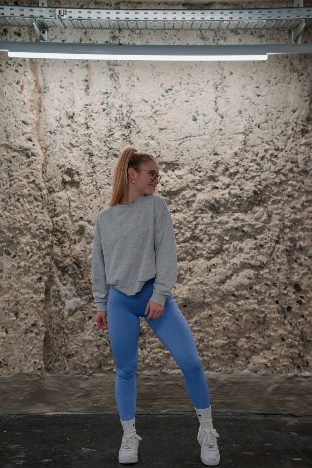 a woman in a grey sweater and blue leggings