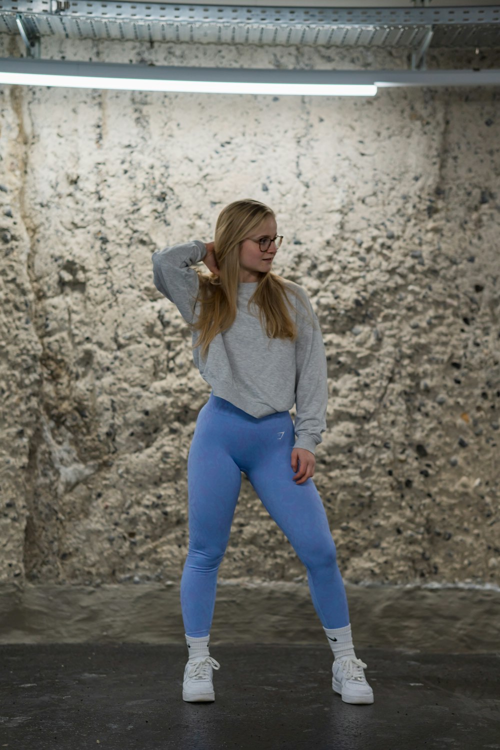 a woman in a grey sweater and blue leggings