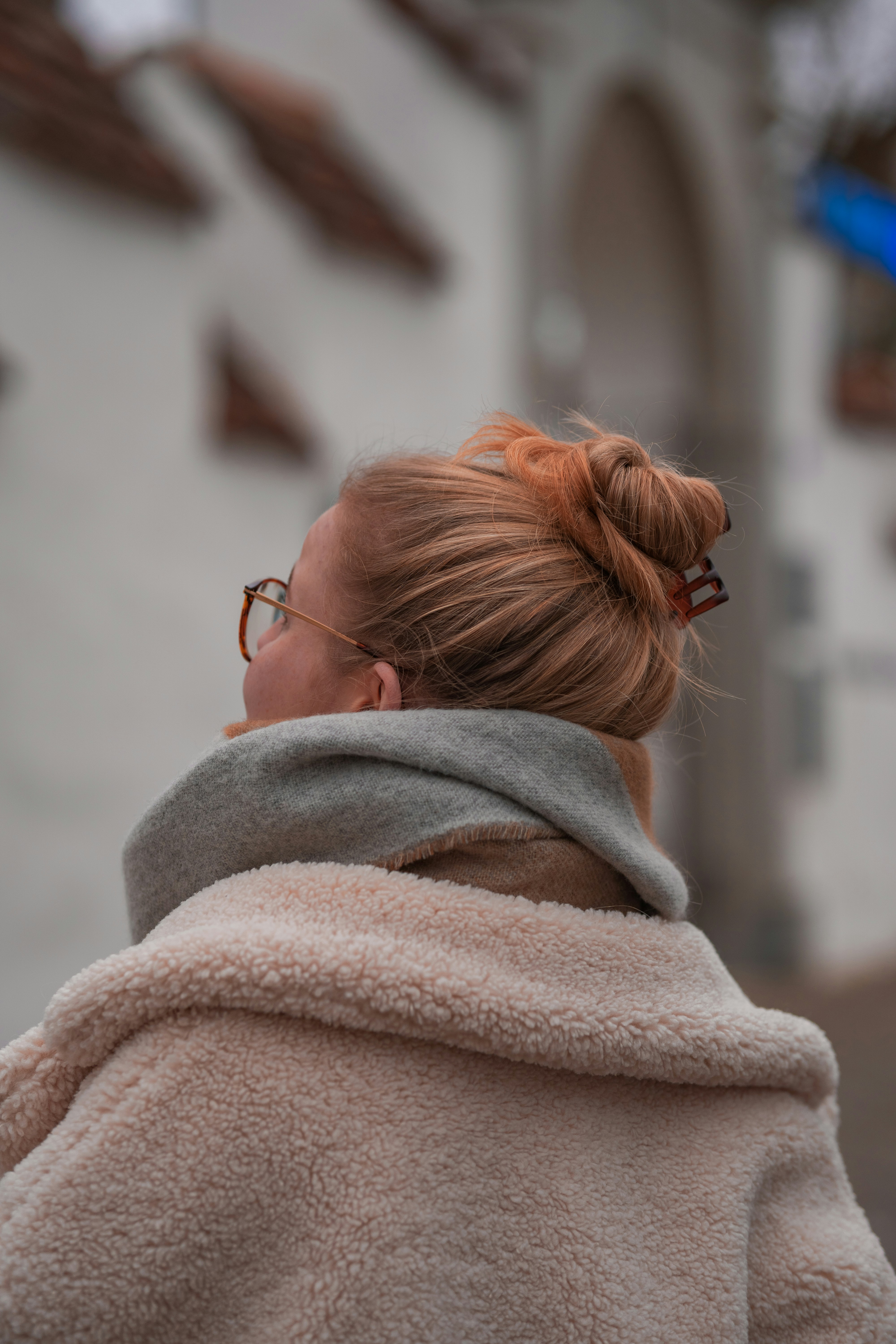 a woman with red hair wearing glasses and a coat