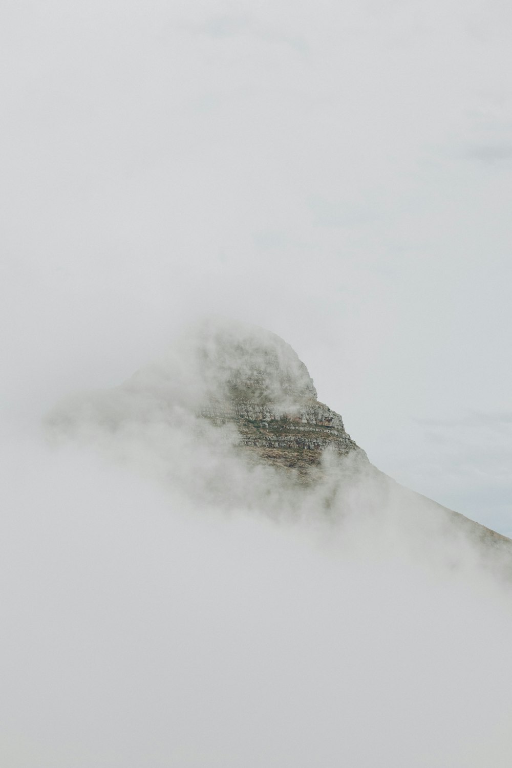 Ein Berg, der an einem bewölkten Tag mit Nebel und Wolken bedeckt ist