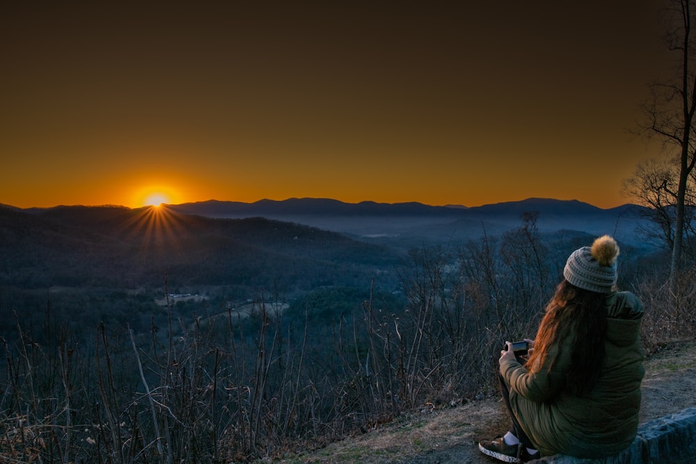 a person sitting on a bench looking at the sunset