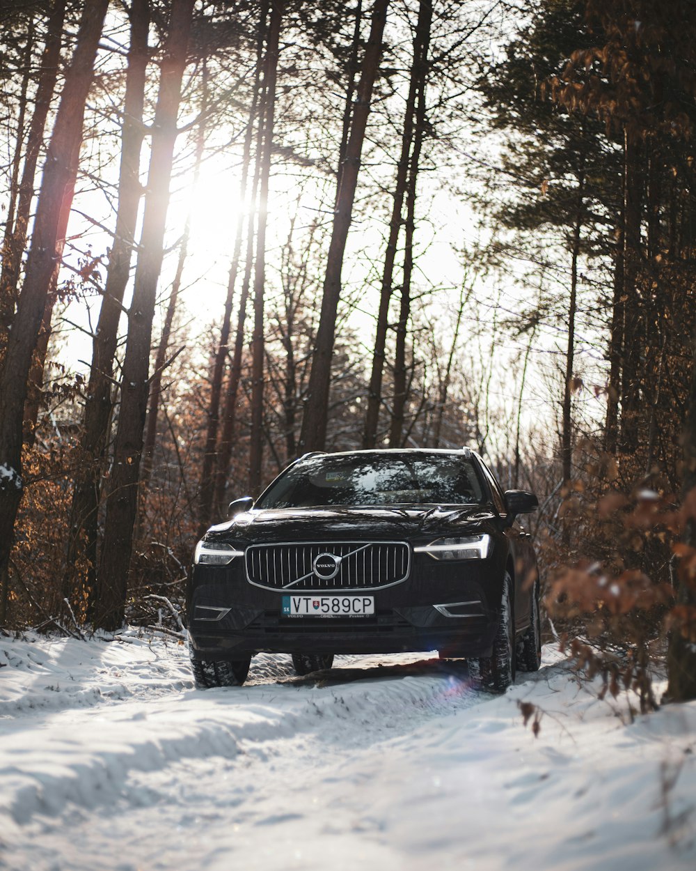 a volvo car driving through the snow in the woods