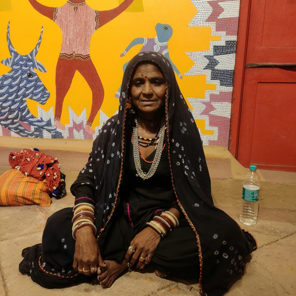 a woman sitting on the ground in front of a painting