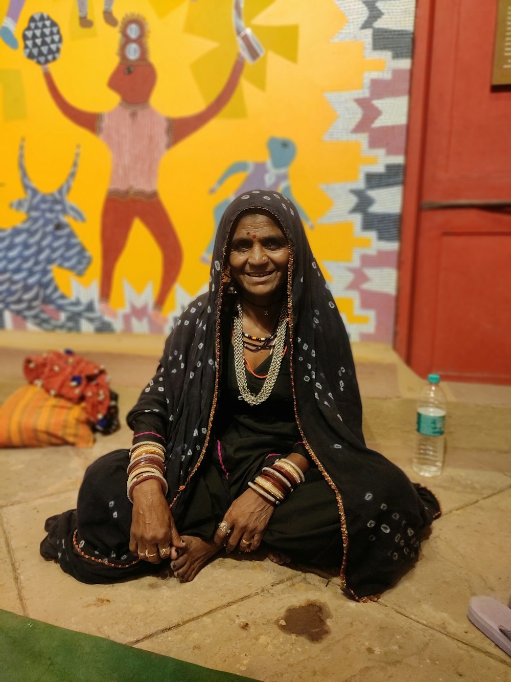 a woman sitting on the floor in front of a painting