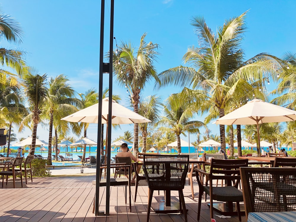 une personne assise à une table sous des parasols