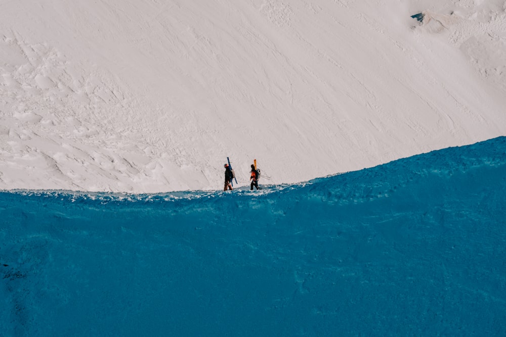 눈 덮인 슬로프 옆에 서있는 두 명의 스키어