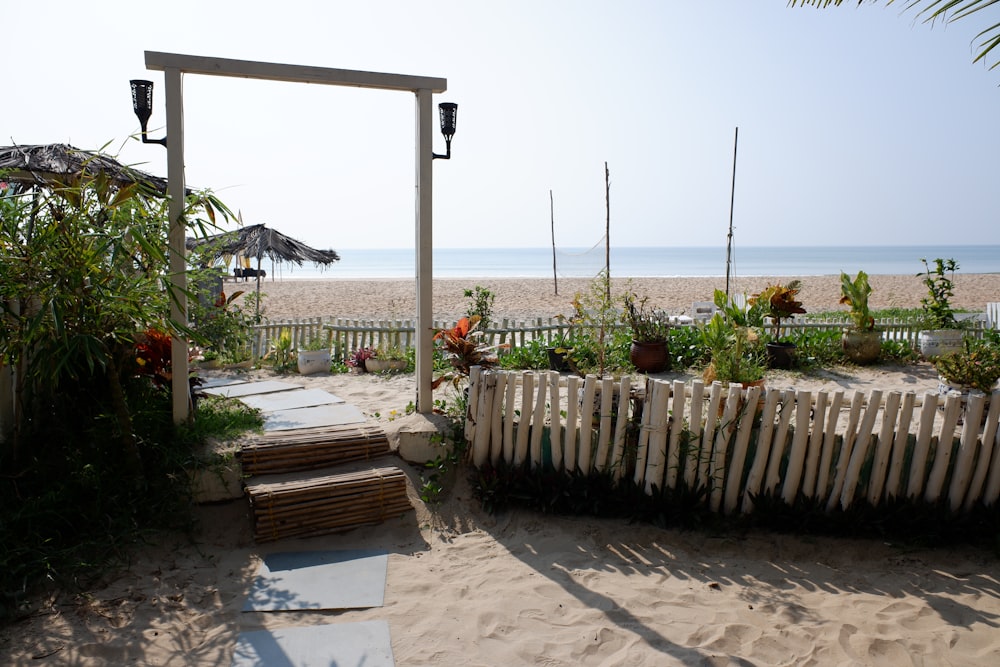 a white fence on a beach with a wooden bench