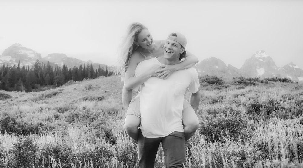 a man carrying a woman on his back in a field