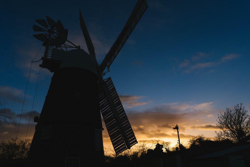 a windmill is silhouetted against the evening sky