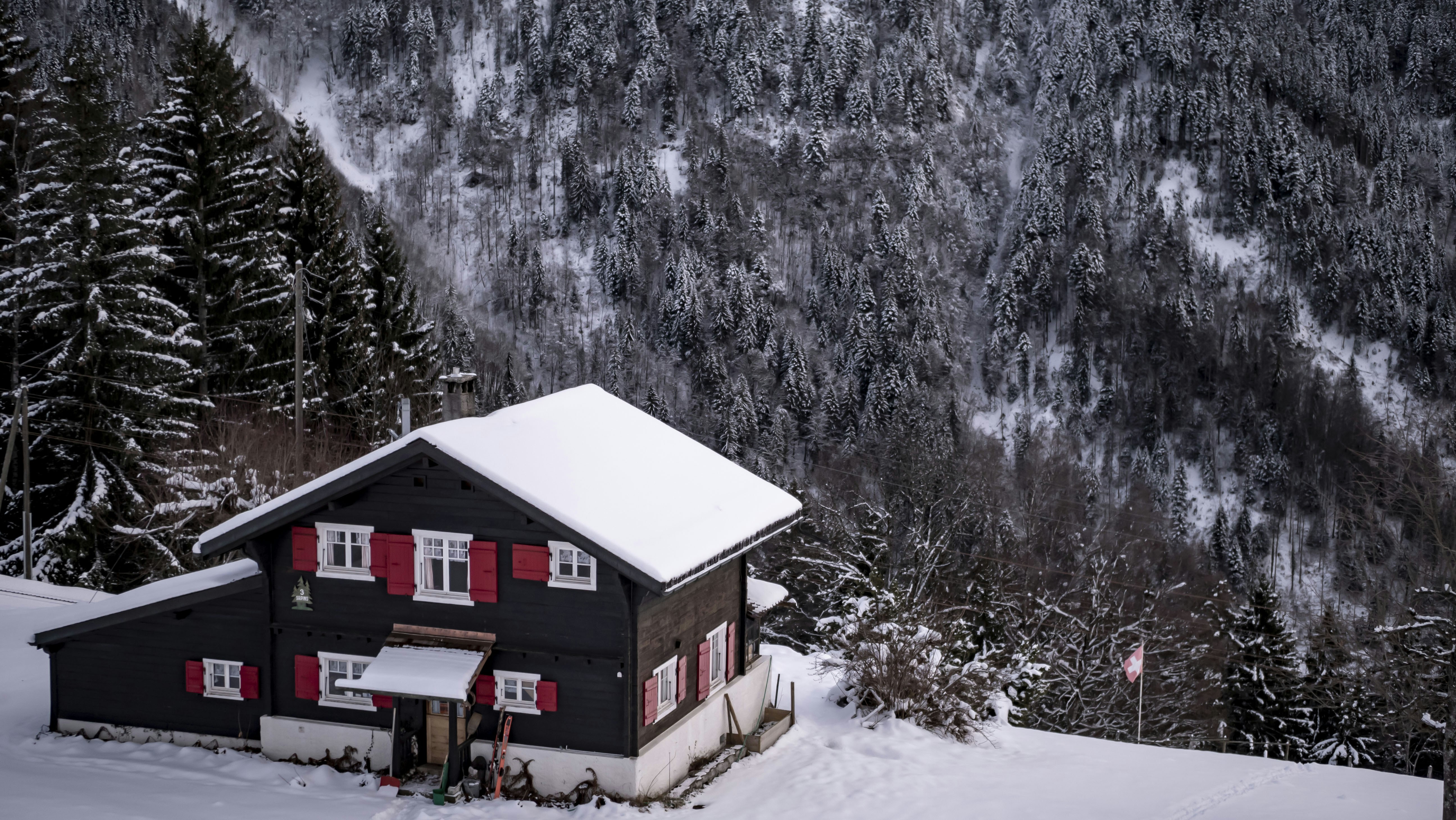 a black house with red shutters in the snow