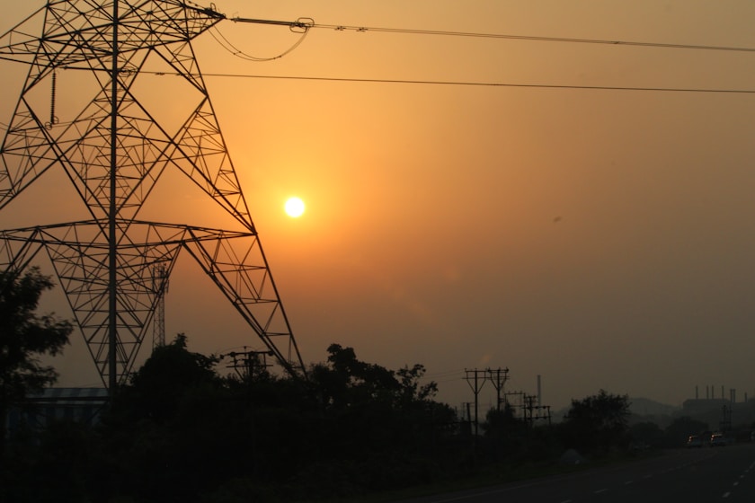the sun is setting behind a power line