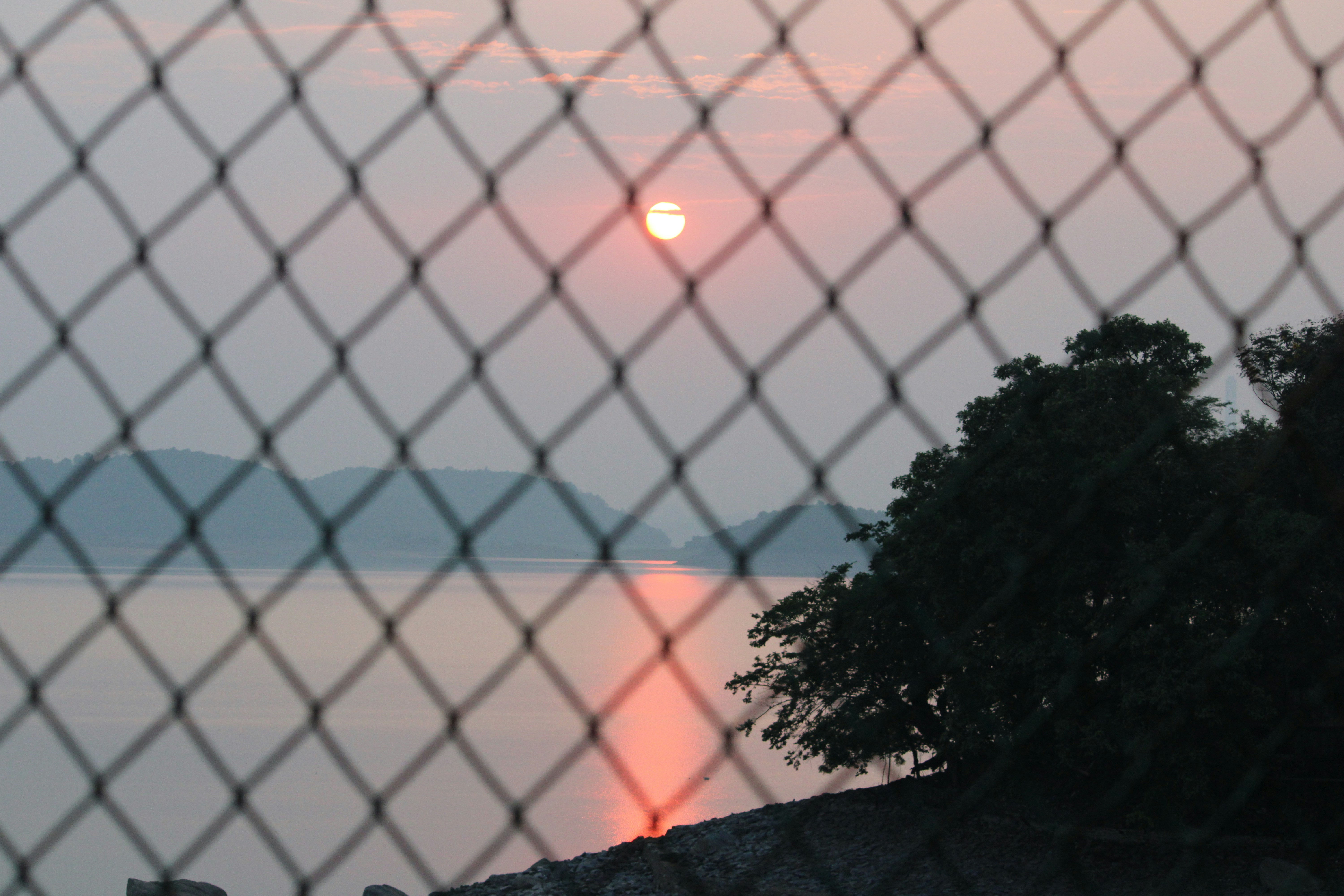 A sunset seen through a chain link fence photo – Free Golden sky Image ...