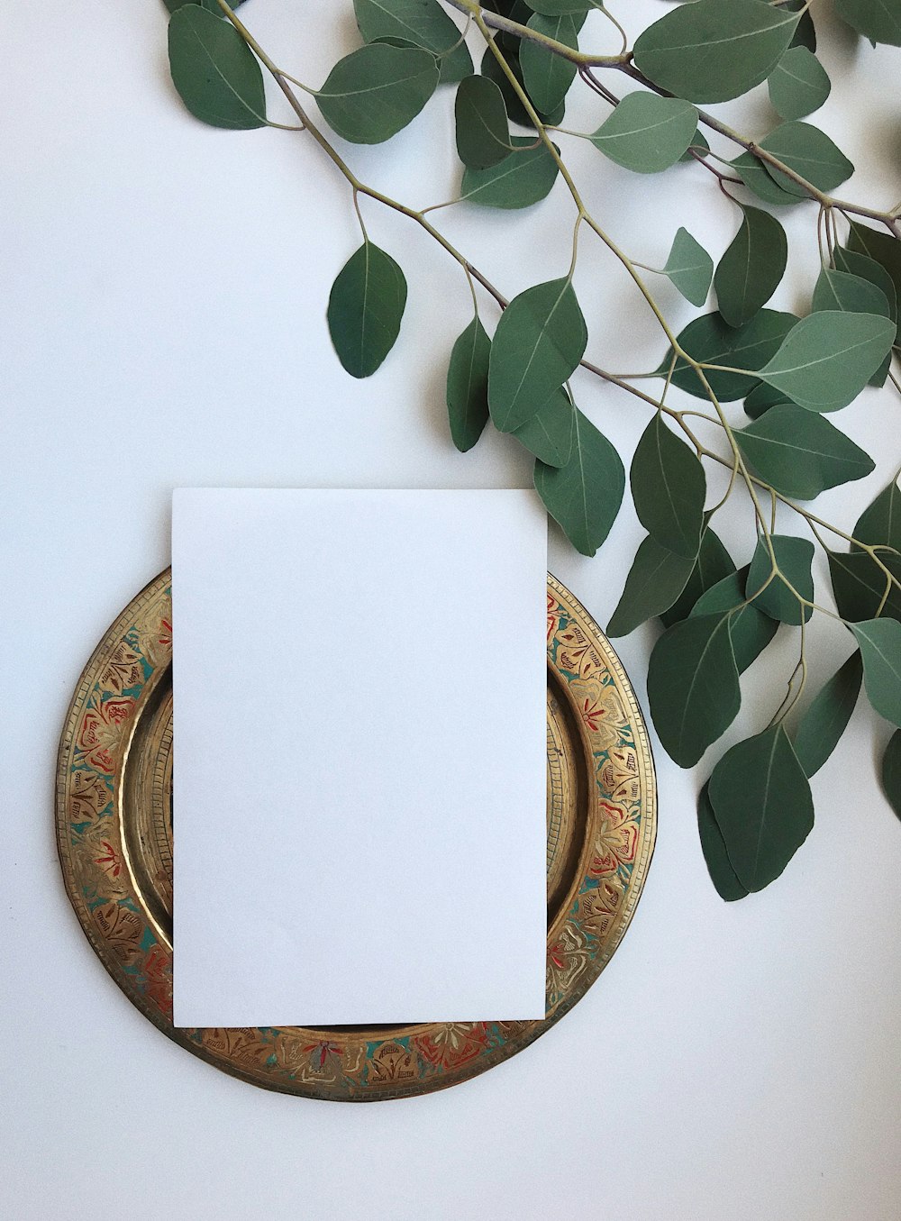 a blank card sitting on a plate next to a plant