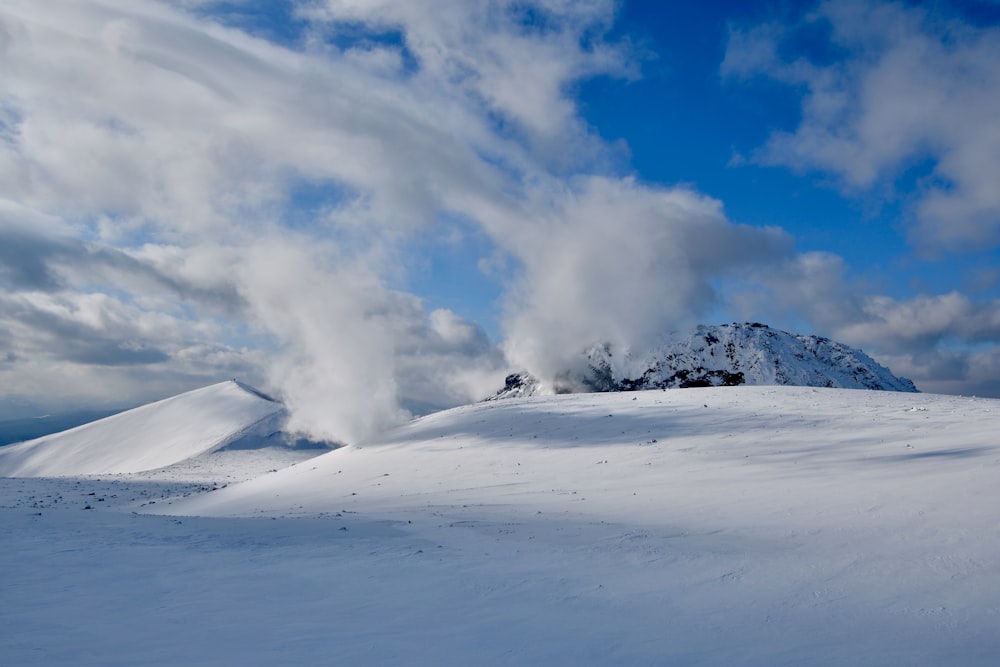 una montaña cubierta de nieve con una nube de humo saliendo de ella