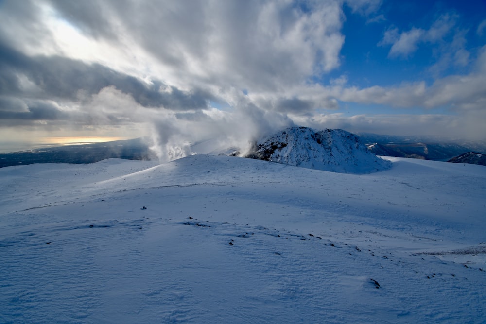 a mountain covered in snow under a cloudy sky