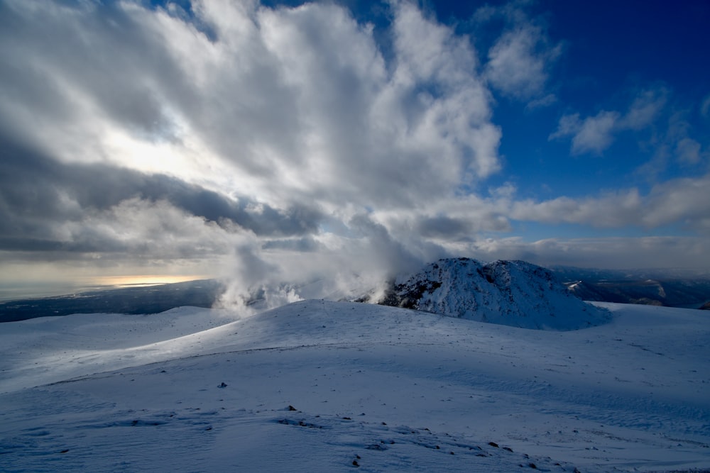 a mountain covered in snow under a cloudy sky