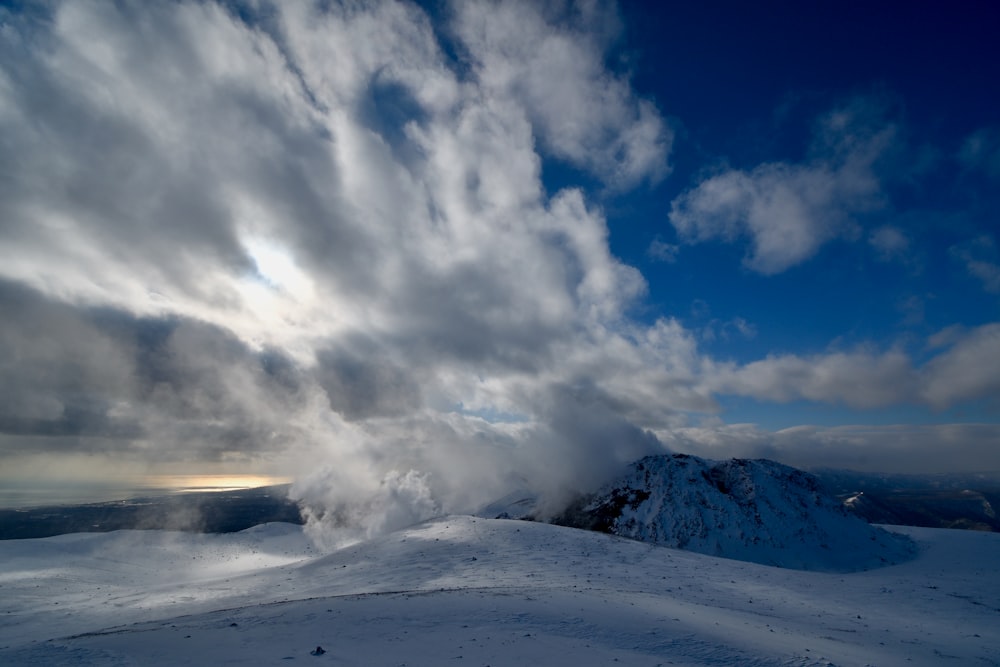 a snow covered mountain under a cloudy sky