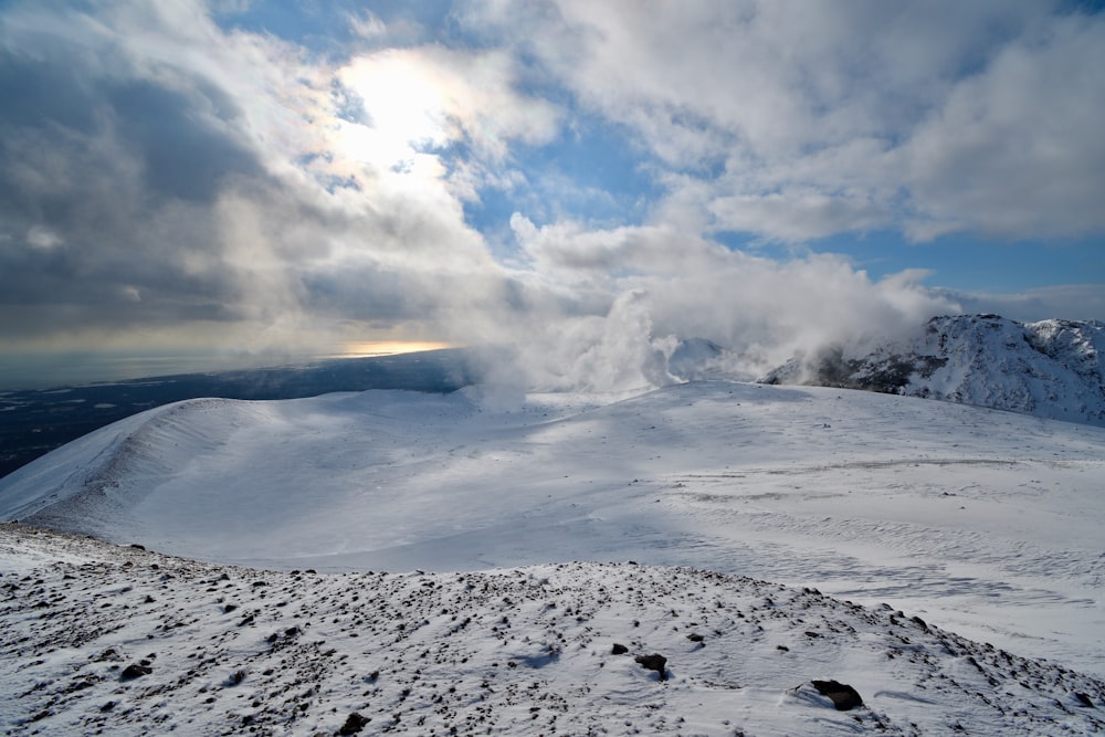 a snow covered mountain with clouds in the sky