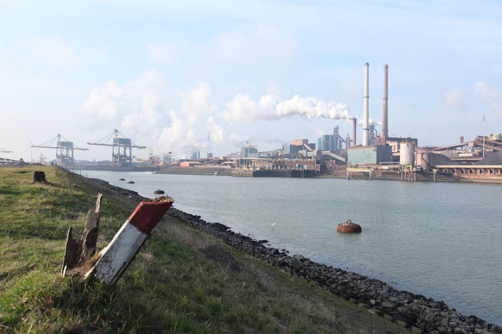 a body of water with a factory in the background