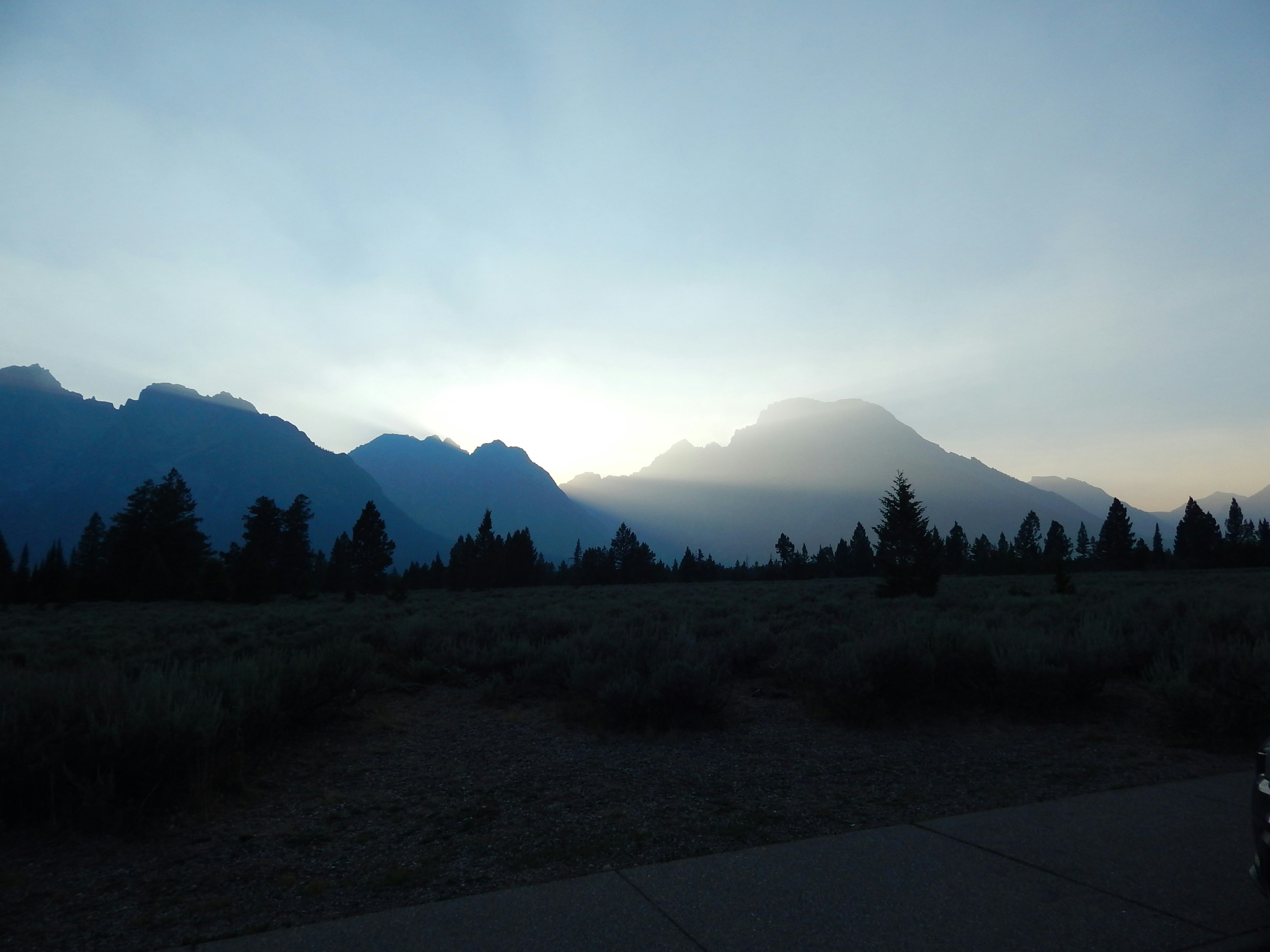 the sun is setting over the mountains in the distance