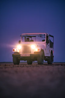 a white jeep driving down a dirt road