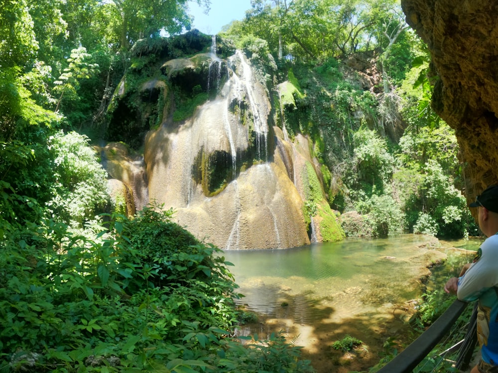 Eine Person, die auf einer Brücke steht und auf einen Wasserfall schaut