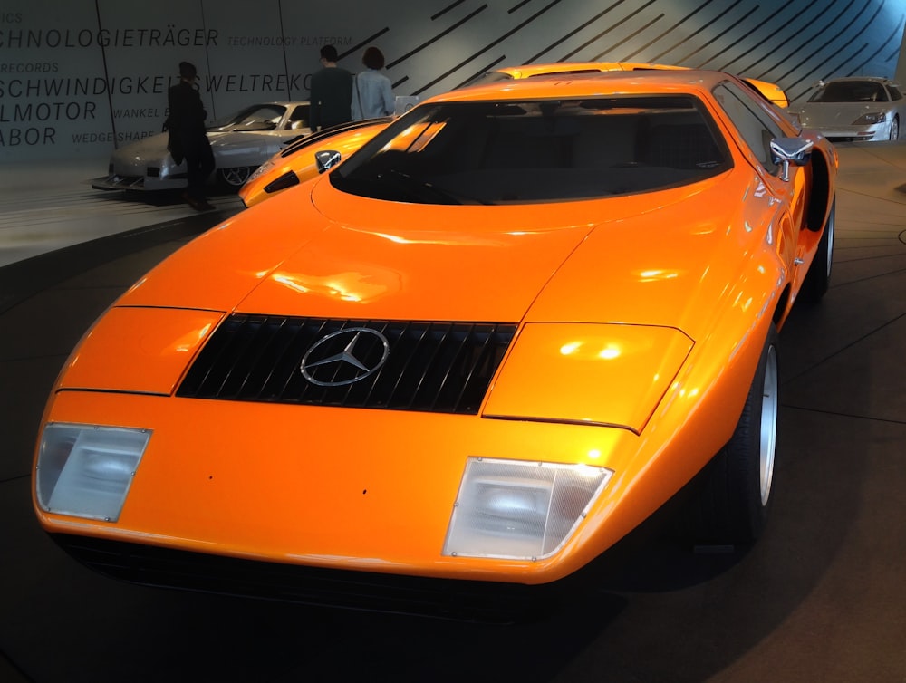 an orange sports car on display at a car show