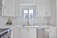 A smiling homeowner inspecting freshly renovated kitchen with bright, modern finishes.
