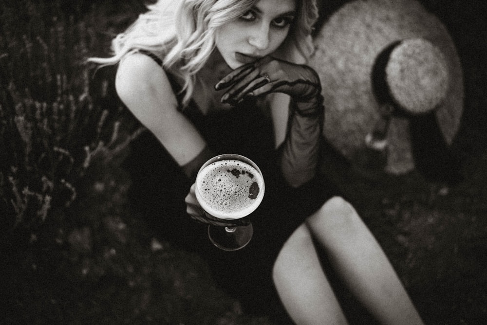 a woman in a black dress holding a cup of coffee