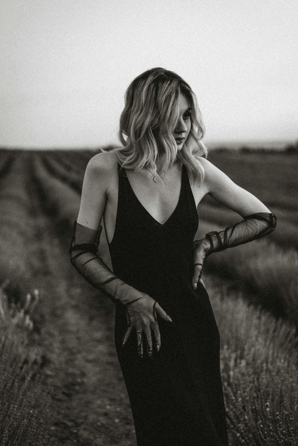 uma mulher em um vestido preto em pé em um campo