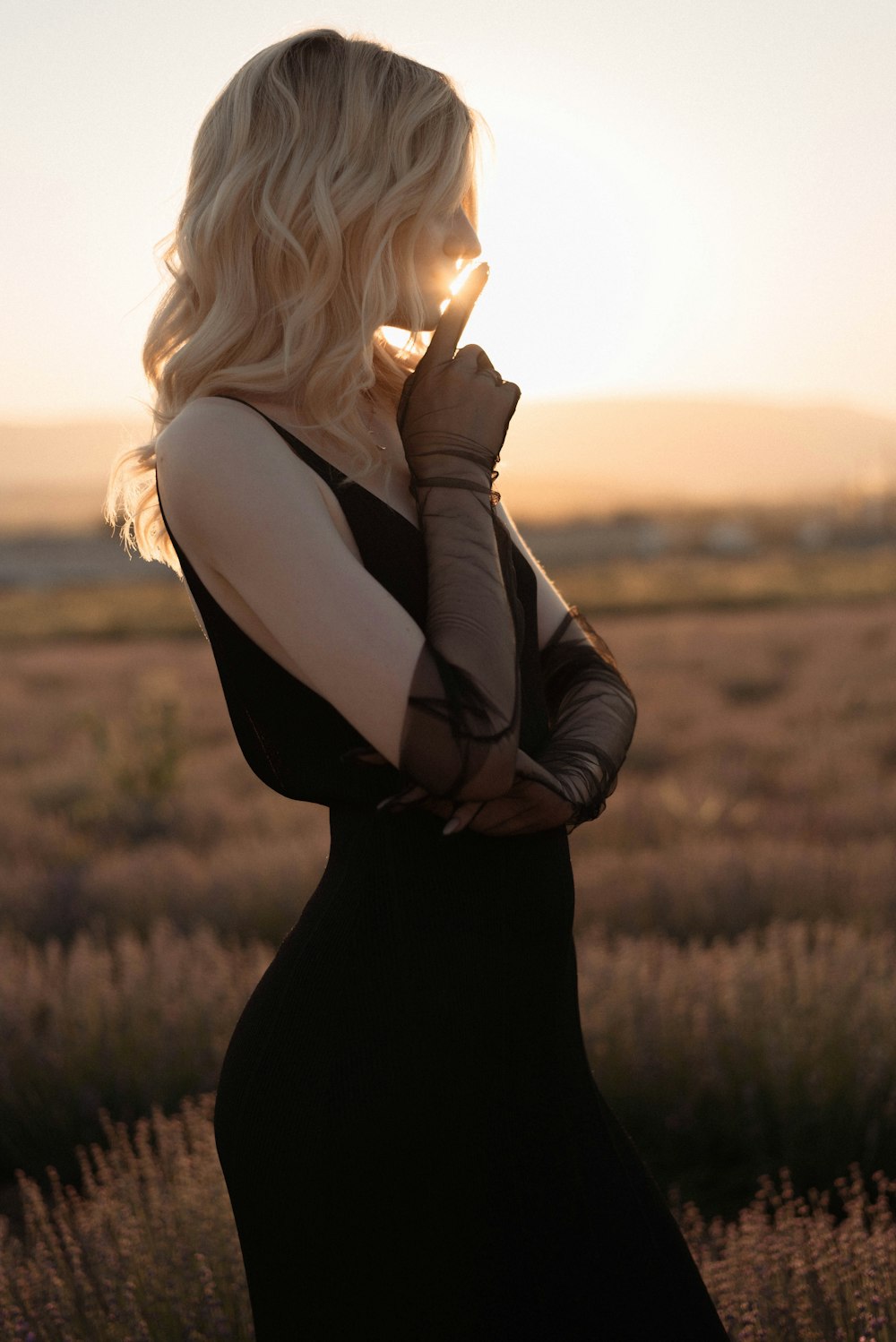 a woman in a black dress standing in a field