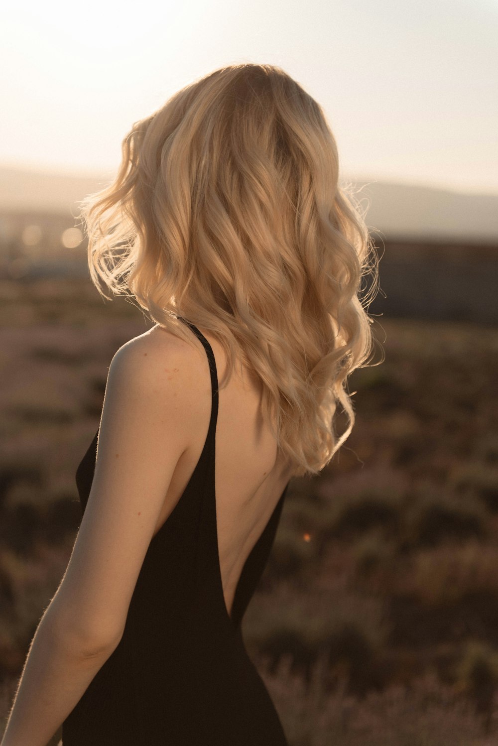 a woman with blonde hair standing in a field