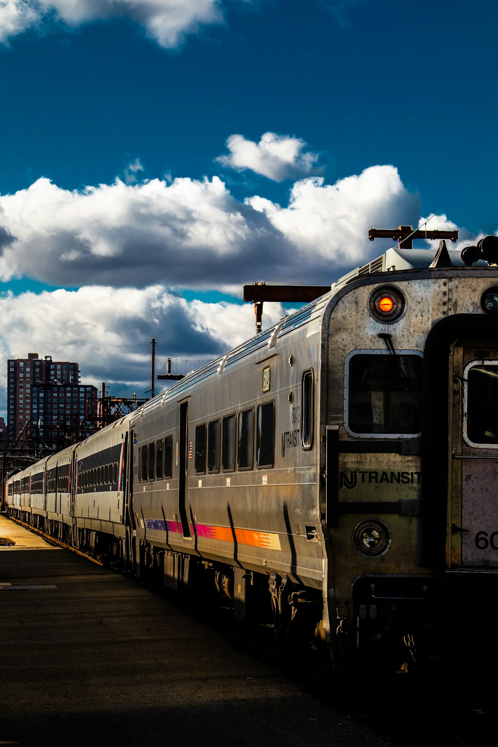 a silver train traveling down train tracks next to tall buildings