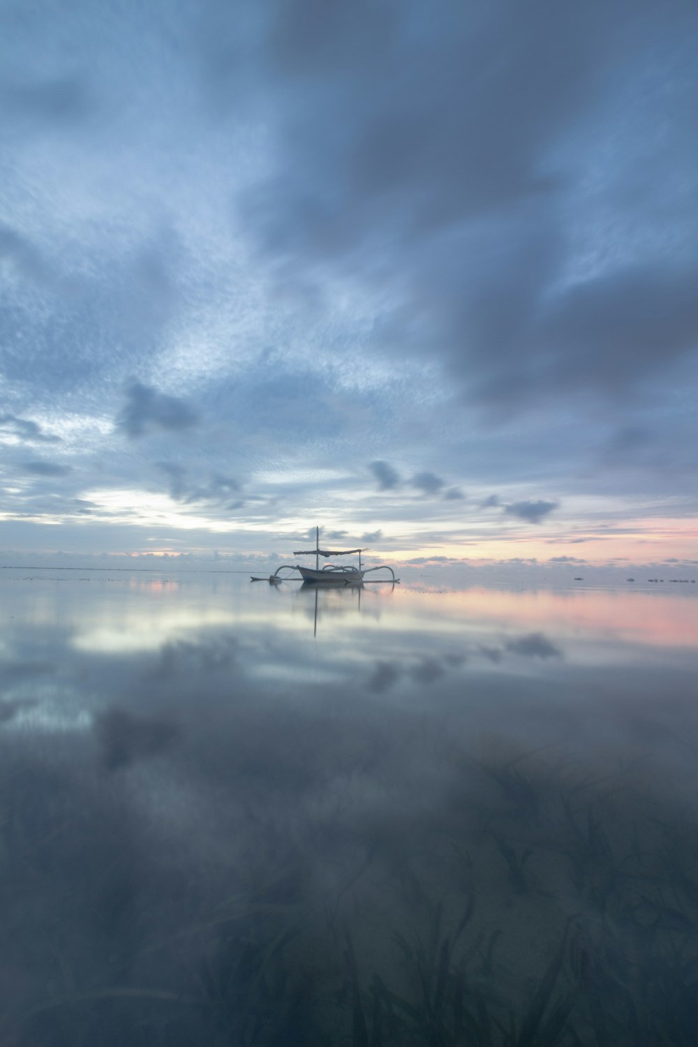 a boat floating on top of a lake under a cloudy sky