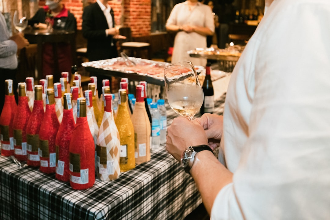 a man standing in front of a table filled with bottles of wine,