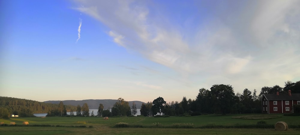 a field with a house and a lake in the distance