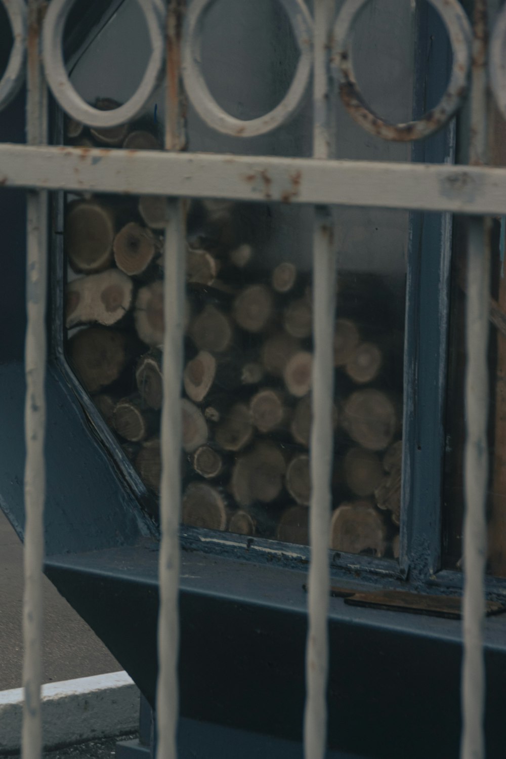 a stack of logs sitting in front of a metal fence