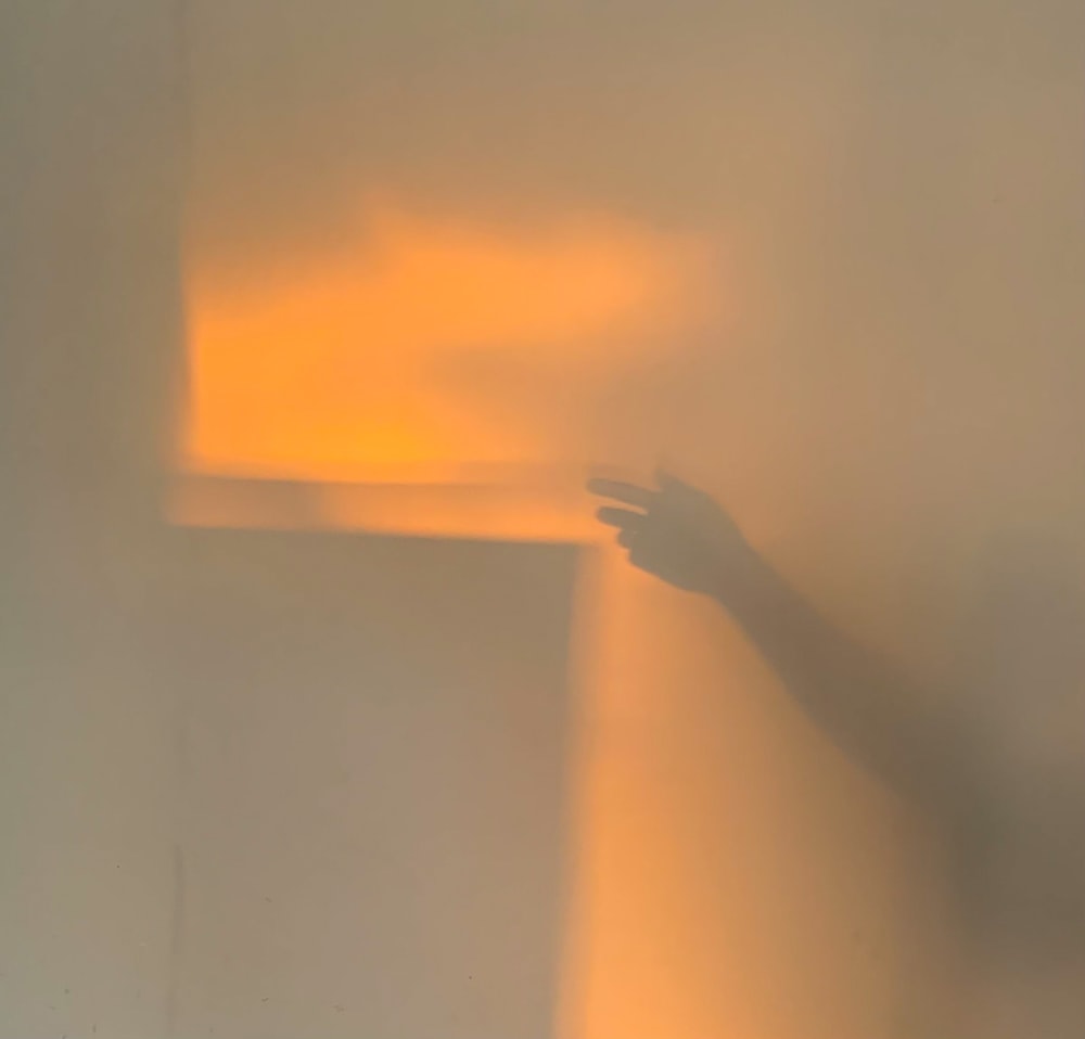 a person's hand on a wall with a shadow cast on it