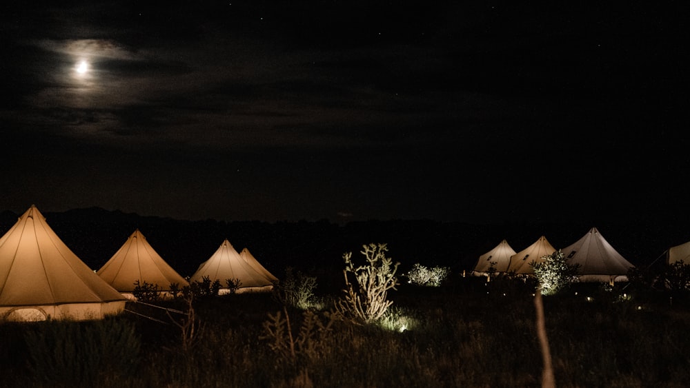a group of tents sitting in a field under a full moon