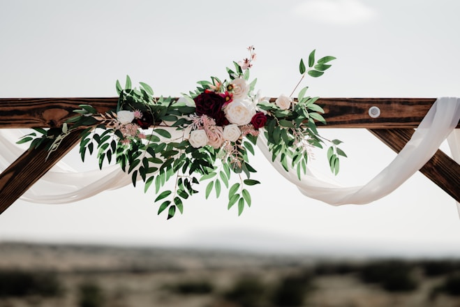 Wedding florist arch installation with white and burgundy florals