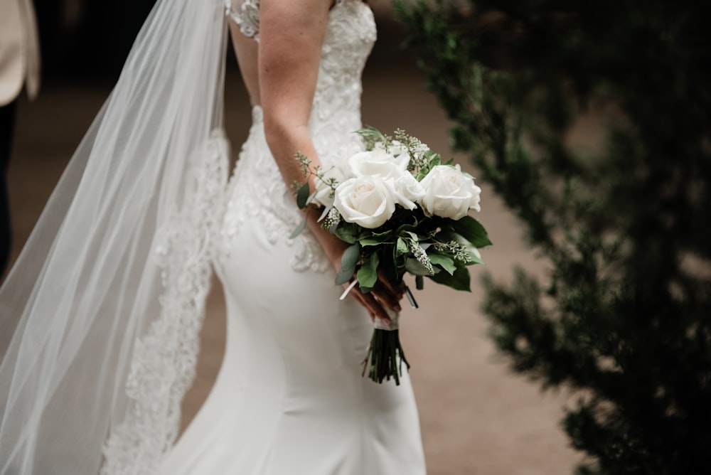 a woman in a wedding dress holding a bouquet of flowers